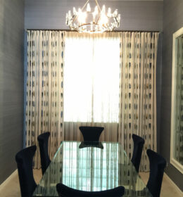 A Glass Dining Table With Wood Chairs and Chandelier
