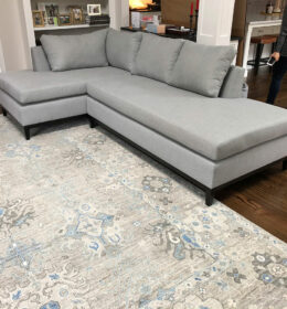 An L Shape Grey Color Sofa With White Ornate Carpet