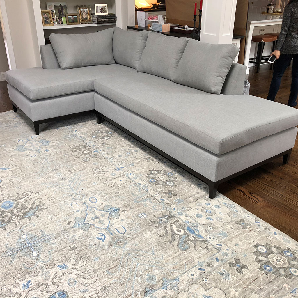 An L Shape Grey Color Sofa With White Ornate Carpet