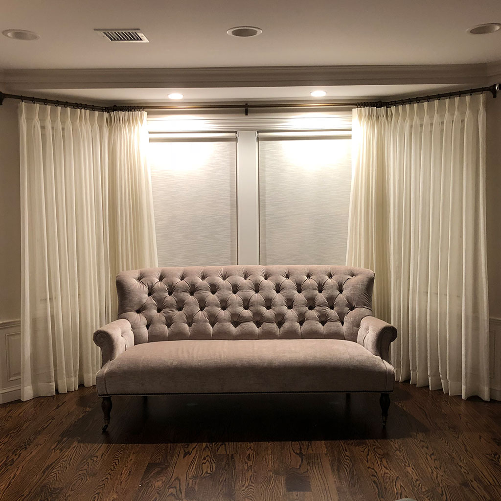 A Beige Paneled Cushion Sofa Infront of White Curtains